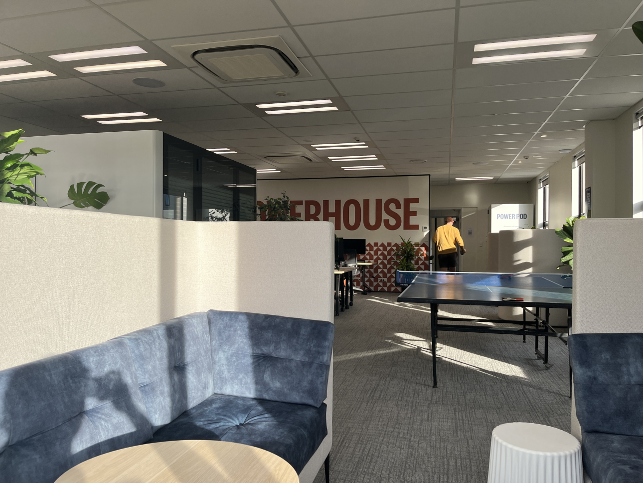 Inside Powerhouse Coworking — the casual lounge with breakout seating, plants and the Powerhouse wall